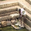 person drinking  water in a spoiled pond