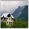 Ice peaks, clouds, green land and house at Khakhnal, Manali