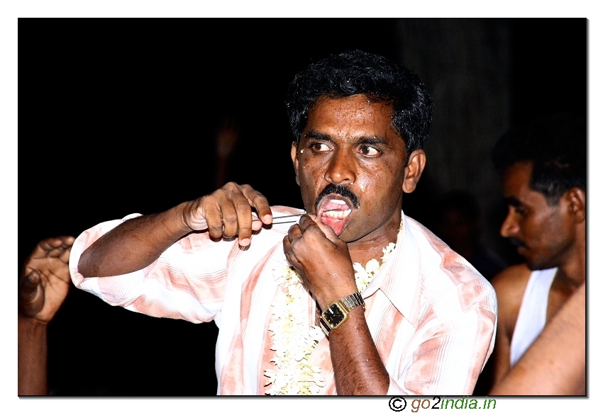 Needle piercing the skin at the cheek of a person during the festival