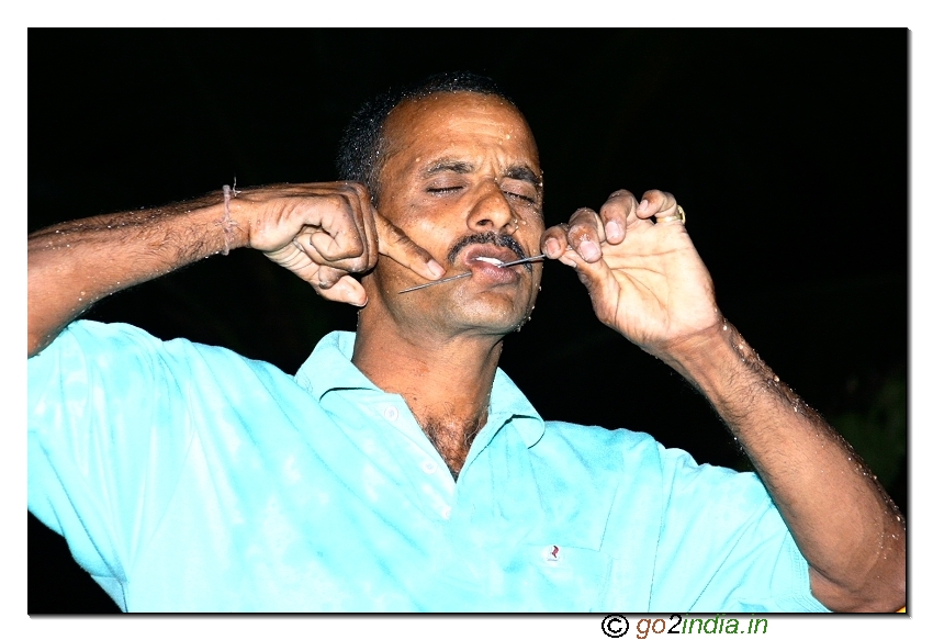 Needle piercing the skin at the cheek of a person during the festival