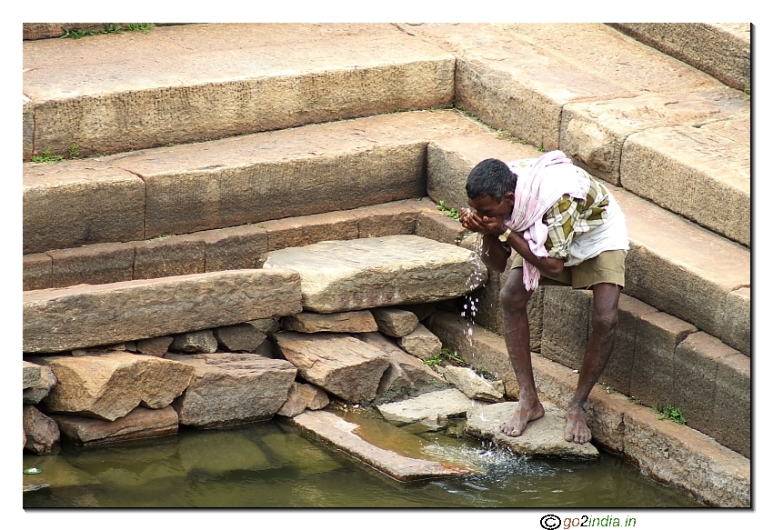 person drinking  water in a spoiled pond